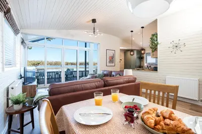 a living room with a table with a plate of food at Sandmartin Lodge a lakeshore haven at Pine Lake Resort in Carnforth