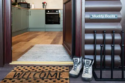 a welcome mat in front of a door with two shoes at Sandmartin Lodge a lakeshore haven at Pine Lake Resort in Carnforth