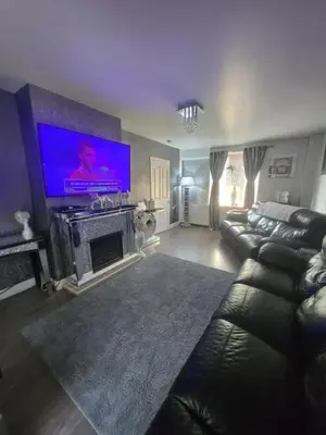 a living room with a couch and a large screen tv at house with hot tub in West Derby