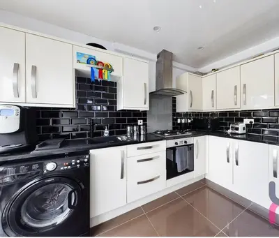 a kitchen with white cabinets and a washer and dryer at house with hot tub in West Derby
