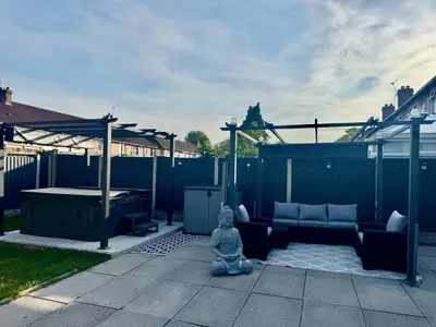 a statue of a meditating person sitting on a patio at house with hot tub in West Derby