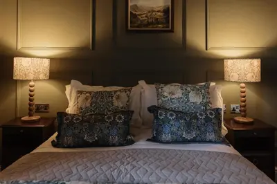 a bedroom with a bed with pillows and two lamps at Cartmel Old Grammar in Cartmel