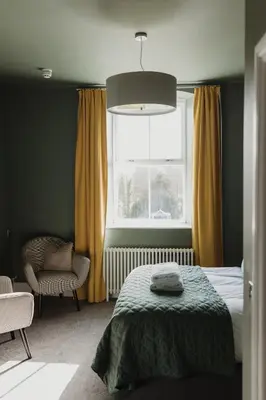 a bedroom with a bed and a window and a chair at Cartmel Old Grammar in Cartmel