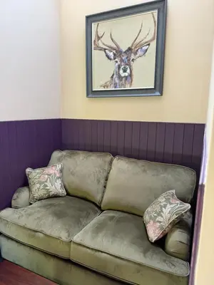 a couch in a room with a picture of a deer at Cartmel Old Grammar in Cartmel
