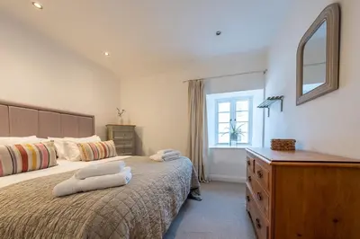 a bedroom with a bed and a dresser and a mirror at Spacious & relaxing cottage stay with free parking in Cark