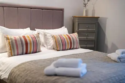 a bed with two towels on top of it at Spacious & relaxing cottage stay with free parking in Cark