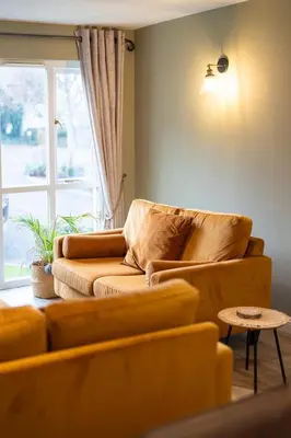 a living room with a couch and a window at Spacious & relaxing cottage stay with free parking in Cark