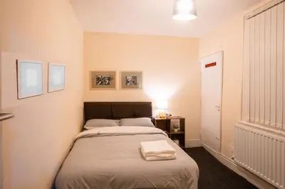 a small bedroom with a bed and a table at Kirkdale Apartment in Liverpool