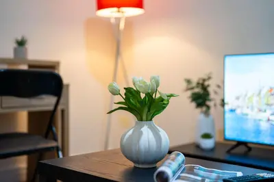a white vase with flowers sitting on a desk at Kirkdale Apartment in Liverpool