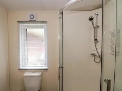 a bathroom with a toilet and a window and a shower at Lakeland Lodge- 3Bed-2 Bath- Private Patio in Carnforth