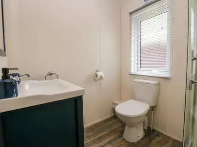 a bathroom with a toilet and a sink and a window at Lakeland Lodge- 3Bed-2 Bath- Private Patio in Carnforth