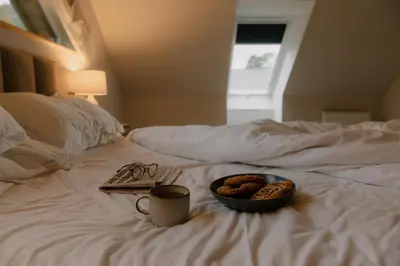 a tray of food and a plate of donuts on a bed at Landal Twin Lakes in Carnforth