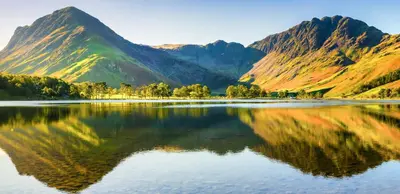 a mountain reflection in a lake with mountains in the background at Landal Twin Lakes in Carnforth