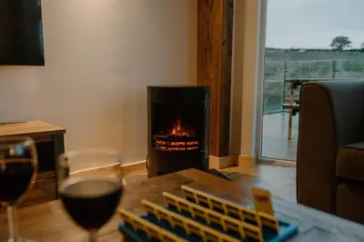 a fireplace in a living room with a glass of wine at Landal Twin Lakes in Carnforth
