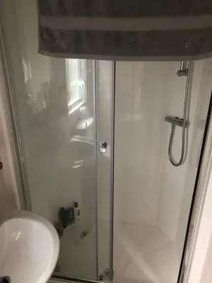 a shower with a glass door next to a sink at Getaway in Longridge