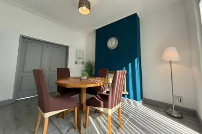 a dining room table with chairs and a clock on a blue wall at Fairburn House - Air Host & Stay - Contractor Friendly in Liverpool