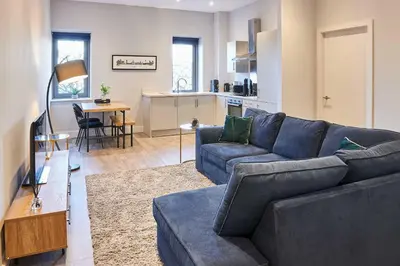 a living room with a blue couch and a kitchen at Host & Stay - Mariposa Waterloo in Sefton