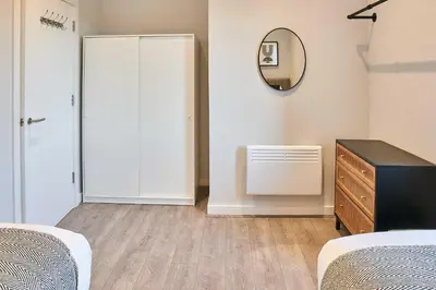a bedroom with two beds and a dresser and a mirror at Host & Stay - Mariposa Waterloo in Sefton