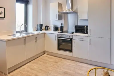 a kitchen with white cabinets and a sink and a microwave at Host & Stay - Mariposa Waterloo in Sefton