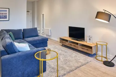a living room with a blue couch and a tv at Host & Stay - Mariposa Waterloo in Sefton
