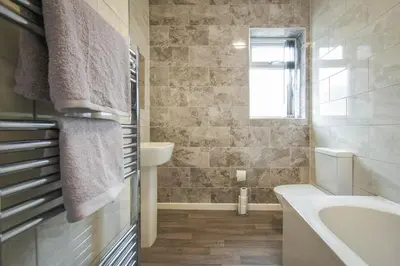 a bathroom with a tub and a sink and a bath tub at Modern House Blackburn in Blackburn