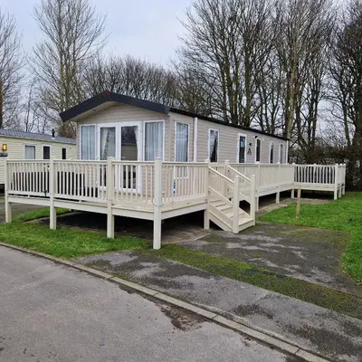 a large white mobile home with a large deck at Lakeland Leaisure park Haven Caravan in Flookburgh