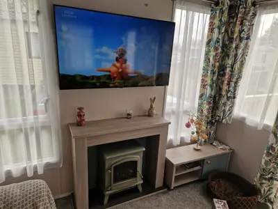 a living room with a fireplace and a tv at Lakeland Leaisure park Haven Caravan in Flookburgh