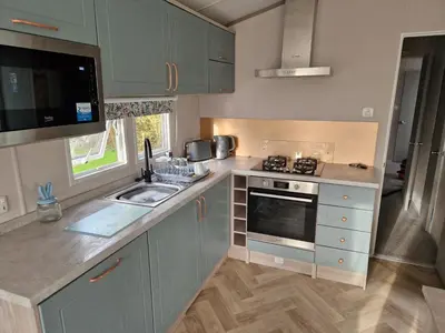 a kitchen with a sink and a stove at Lakeland Leaisure park Haven Caravan in Flookburgh
