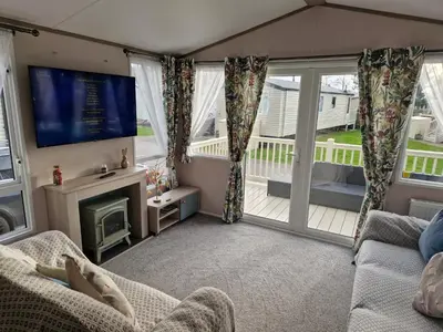 a living room with a fireplace and a tv at Lakeland Leaisure park Haven Caravan in Flookburgh