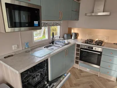 a small kitchen with a sink and a stove at Lakeland Leaisure park Haven Caravan in Flookburgh