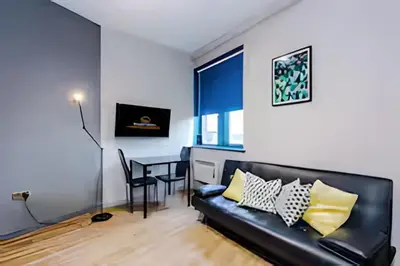 a living room with a black couch and a table at 1 Bedroom Apartment in Wigan Town Centre With Free Parking, by Short Term Digs Short Lets & Serviced Accommodation in Wigan