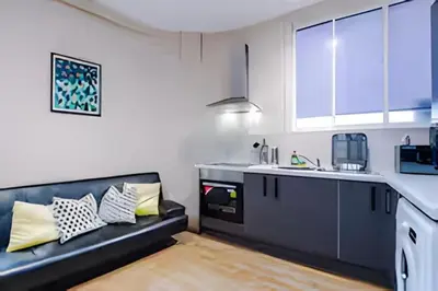 a kitchen with a black couch in a room at 1 Bedroom Apartment in Wigan Town Centre With Free Parking, by Short Term Digs Short Lets & Serviced Accommodation in Wigan