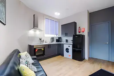 a living room with a couch and a kitchen at 1 Bedroom Apartment in Wigan Town Centre With Free Parking, by Short Term Digs Short Lets & Serviced Accommodation in Wigan
