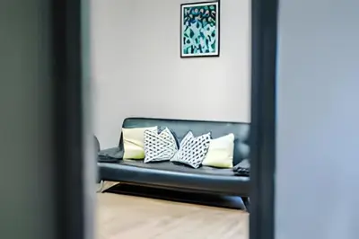 a couch in a living room with pillows on it at 1 Bedroom Apartment in Wigan Town Centre With Free Parking, by Short Term Digs Short Lets & Serviced Accommodation in Wigan