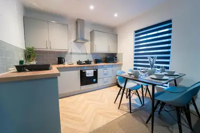 a kitchen with a table and blue chairs at Stylish Self Check In Wigan Town Centre Apartment with Fast WiFi Ideal for Long Stays and Contractor Stays in Wigan