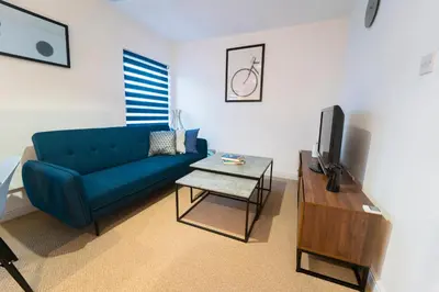 a living room with a blue couch and a table at Stylish Self Check In Wigan Town Centre Apartment with Fast WiFi Ideal for Long Stays and Contractor Stays in Wigan