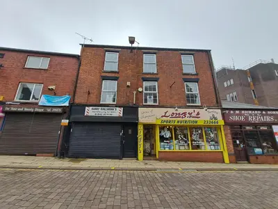 a brick building on a street with a store at Stylish Self Check In Wigan Town Centre Apartment with Fast WiFi Ideal for Long Stays and Contractor Stays in Wigan