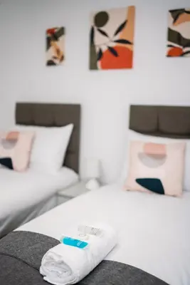 a hotel room with two beds with towels on the bed at Stylish Self Check In Wigan Town Centre Apartment with Fast WiFi Ideal for Long Stays and Contractor Stays in Wigan