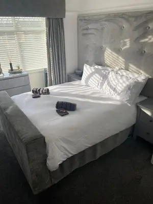 a bedroom with a large bed with white sheets at Stylish Home Away From Home! 6 Minutes from Beach! in Wirral