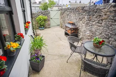 a patio with a table and chairs and a stone wall at Mill Cottage in Clitheroe
