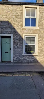a building with a green door and two windows at Mill Cottage in Clitheroe