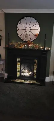 a fireplace in a living room with a clock above it at Mill Cottage in Clitheroe