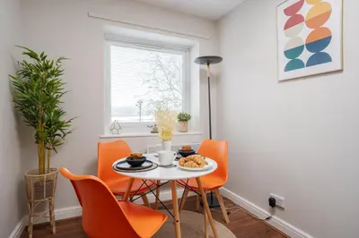 a dining room with orange chairs and a table with food on it at Cozy Waterfront Apartment - Free Parking & Wi-Fi in Preston