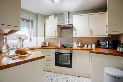 a kitchen with white cabinets and a stove top oven at Cozy Waterfront Apartment - Free Parking & Wi-Fi in Preston