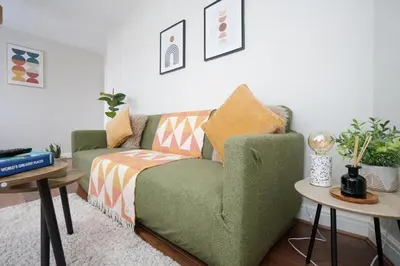 a living room with a green couch and two tables at Cozy Waterfront Apartment - Free Parking & Wi-Fi in Preston