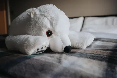 a white teddy bear laying on a bed at Dockside Escape By Royal Albert Dock in Liverpool