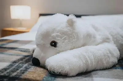 a stuffed white teddy bear laying on a bed at Dockside Escape By Royal Albert Dock in Liverpool