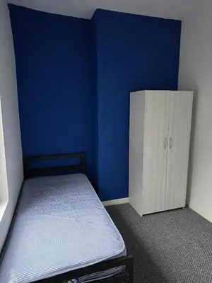 a blue room with a bed and a cabinet at 167,ormskirk road in Wigan