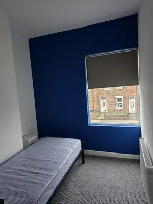 a bedroom with a blue wall and a window at 167,ormskirk road in Wigan