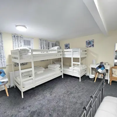 a bedroom with white bunk beds in a room at 100 Pipers Hotel in Blackpool